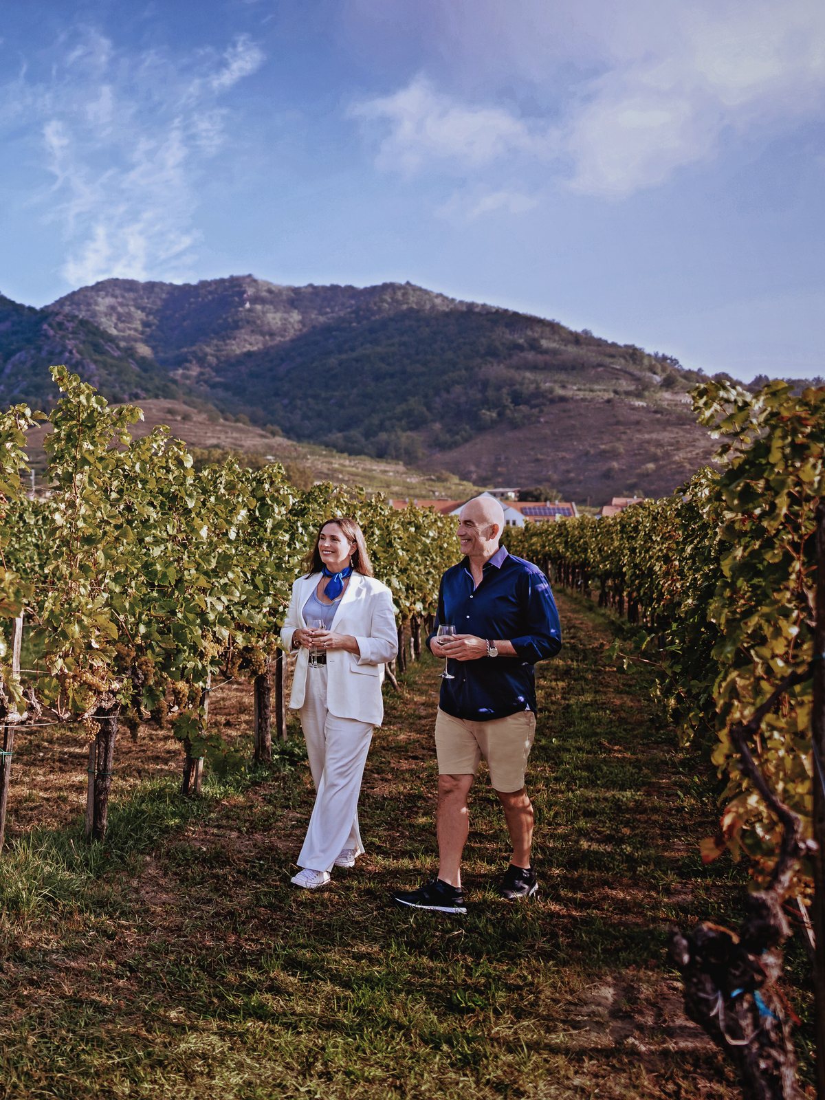 A couple enjoying wine in a European vineyard on a river cruise vacation planned by T&M Travel